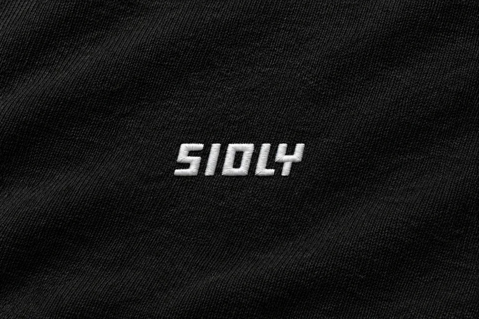 Nahaufnahme des weiß gestickten SIOLY-Logos auf schwarzem Fleece, Vorab-Visualisierung